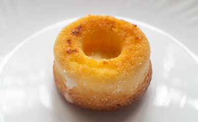 Small yellow donut on white plate close up 