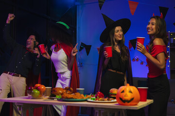 Dinner and group of people celebrating together at Halloween party. Friends are happy and celebrating with food, wine and friendship of love and cheers of champagne at the event.
