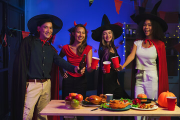 Dinner and group of people celebrating together at Halloween party. Friends are happy and celebrating with food, wine and friendship of love and cheers of champagne at the event.