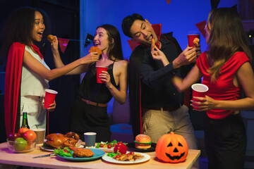 Dinner and group of people celebrating together at Halloween party. Friends are happy and celebrating with food, wine and friendship of love and cheers of champagne at the event.