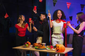 Dinner and group of people celebrating together at Halloween party. Friends are happy and celebrating with food, wine and friendship of love and cheers of champagne at the event.