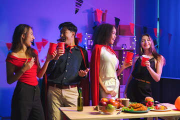 Dinner and group of people celebrating together at Halloween party. Friends are happy and celebrating with food, wine and friendship of love and cheers of champagne at the event.