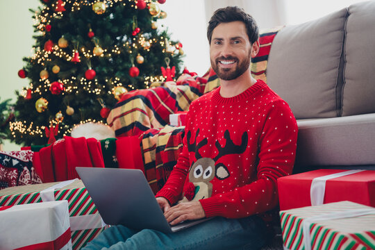 Portrait of nice young man juse laptop sweater christmas holiday time flat indoors