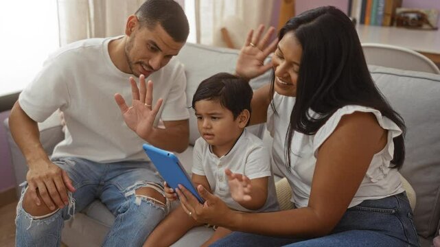 Latin family including man woman and child sitting on couch having video call on tablet at home with love and togetherness