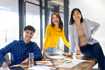 Smiling diverse team collaborating on interior design project with sketches and notes at office