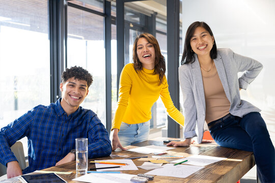 Smiling diverse team collaborating on interior design project with sketches and notes at office