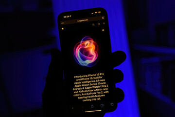 Fototapeta premium Paris, France - Sep 8, 2024: Vertical shot of a male hand holding the iPhone 16 Pro Max with a blue background, showcasing the introduction from Apple's latest keynote. 