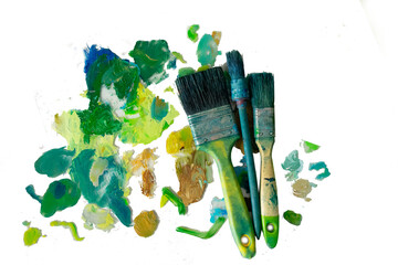 strokes of green paint on a palette, brushes for oil paints on a white background