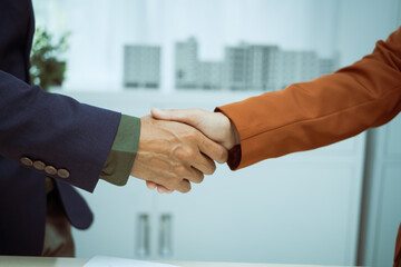  A businessman shakes hands with a customer in the sales office after agreeing to sign a contract...