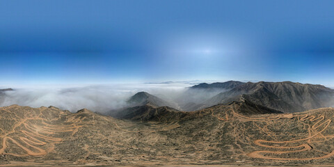 A panoramic shot of a mountain range with a cloudy sky in the background