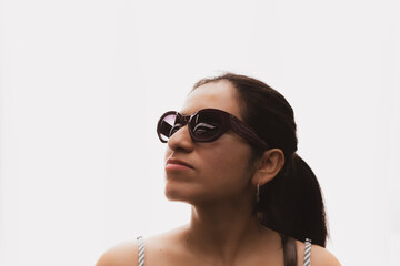 Woman with glasses and in front of a white background looks up in profile.
