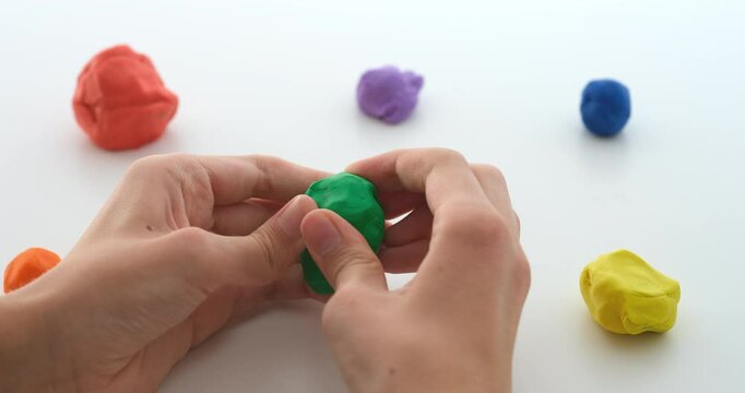 A boy squishing a ball of play clay. Close up.