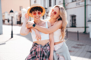 Two young beautiful smiling hipster female in trendy summer white t-shirt and shorts clothes. Sexy carefree women posing in the street. Positive models having fun, hugging and going crazy