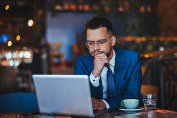 Focused Businessman Working on Laptop in Cozy Cafe Setting