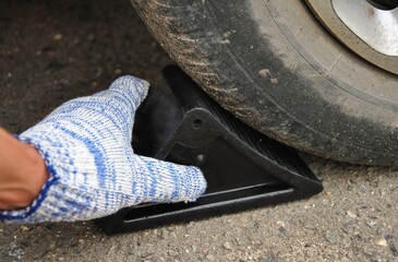 close-up of a wheel chock being installed under a car wheel. safety when using a car