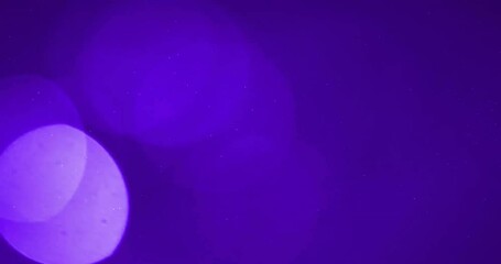 Animation of glowing light spots moving over purple background - Powered by Adobe