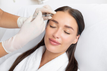 Beautiful lady getting corrective dermal aesthetic improvement treatment and receiving safe...