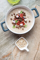 Breakfast oatmeal with fresh figs in a serving pan, flat lay on a grey and roseate granite background, vertical shot