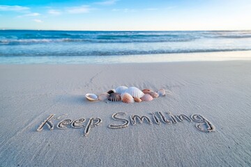 Inspirational beach message with seashells and the words 'Keep Smiling'.