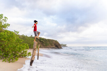 Young man meditating on a log with one foot