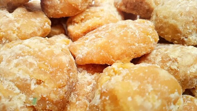 Jaggery or Gur pieces texture background rotating. Organic brown cane sugar pieces close up shot