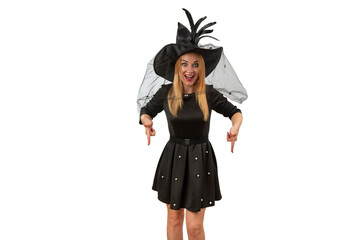 Happy smiling woman in black witch hat and black dress points her fingers down. White background. Mockup. Halloween costume party