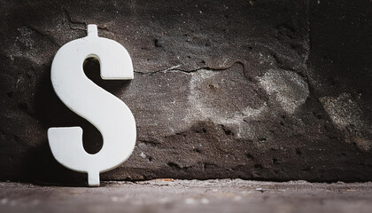 Stone dollar symbol on dark abstract rough background. Money and finance concept. Grunge wall