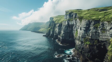 Stunning coastal cliffs rise from the deep blue ocean under a bright sky. Waves crash against rocks, creating a beautiful seascape.