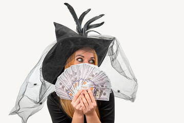 Woman wearing a witch costume for Halloween is hiding her face behind a fan of money