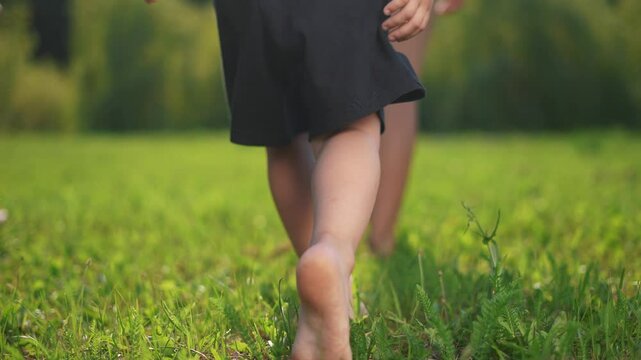 A group of children are running barefoot on the grass. Foot walk nature concept. barefooted walking on grass. A group of children are barefooted walking lifestyle on the grass.