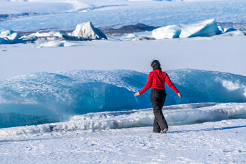 Woman walking on the ice of frozen Jokulsarlon lake during winter in Iceland