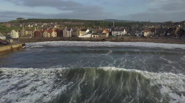 Aerial view of picturesque Eyemouth town with charming buildings and tranquil waves along the coastline, Scottish Borders, United Kingdom.