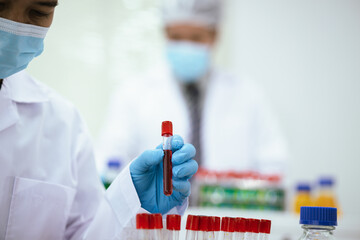 Professional female scientist in laboratory studying chemical reactions, analyzing liquids in beakers, focusing on research, conducting experiments in microbiology, medical development, biotechnology.