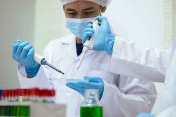 Two Asian scientists working at night in a state-of-the-art laboratory, analyzing data on a laptop while conducting biotechnology experiments with advanced equipment, DNA samples and test tubes.