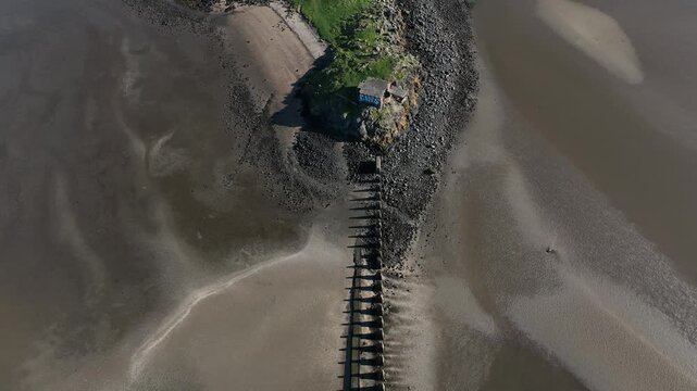 Aerial view of tranquil Cramond Island with a scenic pathway and bridge along the serene shoreline, Edinburgh, United Kingdom.