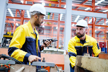 Male engineer works and inspects machinery at a metal sheet factory.