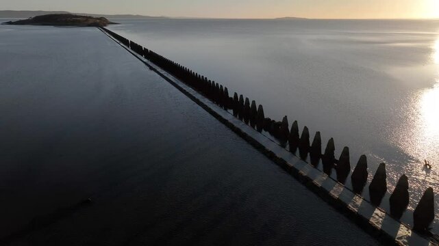 Aerial view of tranquil Cramond Island with serene waters and a scenic pathway at sunset, Cramond, Edinburgh, United Kingdom.