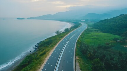 Obraz premium Majestic Coastal Highway Winding Through Lush Green Landscapes and Towering Mountains