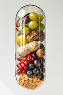 Vitamin supplements in a transparent capsule on an isolated white background. Concept of capsule active supplements derived from natural food. Mixed media.
