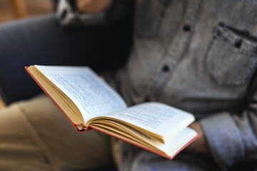 Fototapeta premium Indoor shot of mature man sitting on arm chair and reading a book at home.