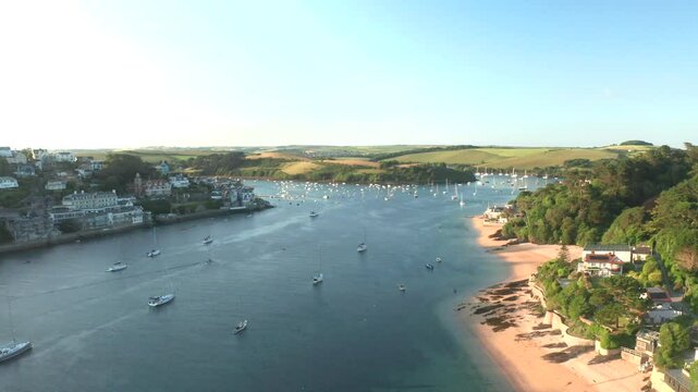 Aerial view of beautiful Mill Bay with boats and houses surrounded by tranquil trees and cliffs, Devon, United Kingdom.