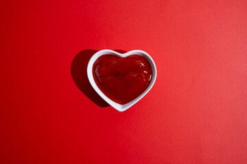 Tasty ketchup in a white bowl on a colored background. Portion of tomato sauce
