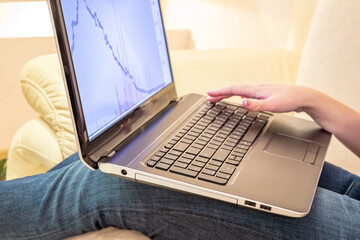 Side view of young woman typing on laptop while sitting on the couch