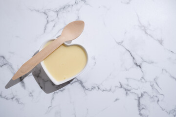 Condensed milk with spoon on light background. Sweet sauce dessert
