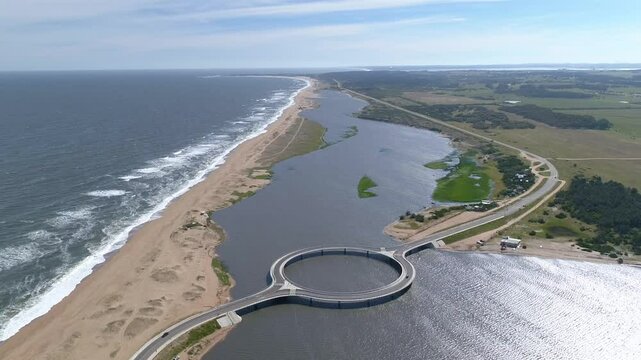 Aerial view of Laguna Garzon Bridge with cars crossing over the tranquil ocean and beautiful coastline, Maldonado, Uruguay.
