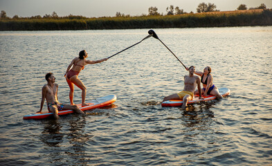 Group of friends on sup board enjoying a day at lake during sunset.