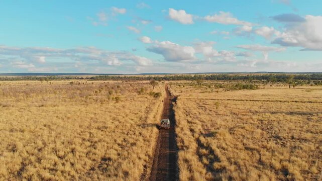 Aerial view of a dry outback landscape with a dirt road and vehicles, Emerald, Queensland, Australia.