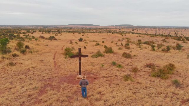 Aerial view of vast outback landscape with a solitary man and a cross amidst the bush, Mackenzie River, Queensland, Australia.
