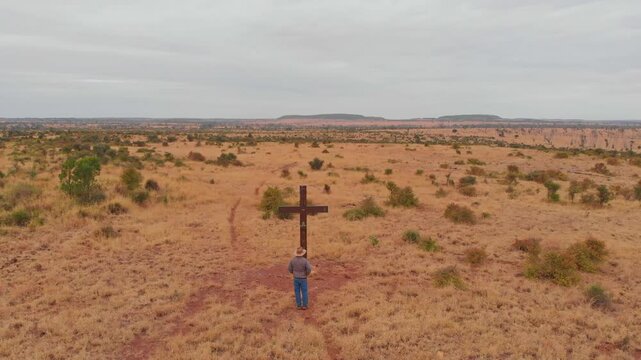 Aerial view of a vast and barren outback landscape with a solitary man and a cross, Mackenzie River, Queensland, Australia.