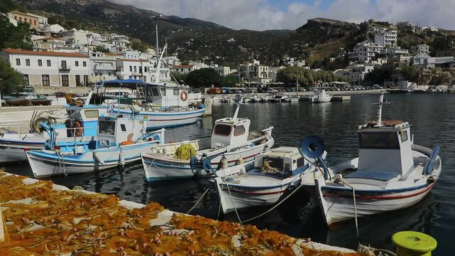Traditional fishing boats with drying fishing nets framed by the impressive Athera mountains massif at the cozy port of  Ikaria's capital Agios Kirykos.